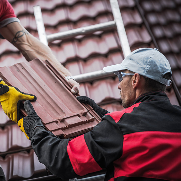 Couvreurs de Entreprise Clivaz remplaçant des tuiles sur une toiture